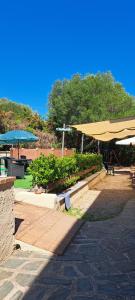 a park with benches with umbrellas and tables at Camerota Basic Appartamenti in Lentiscosa