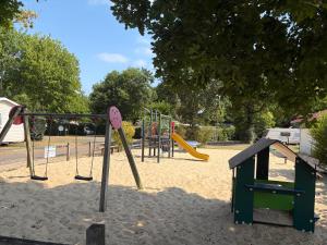 an empty playground with swings and a slide at Mobil-home proche plage in Saint-Julien-en-Born