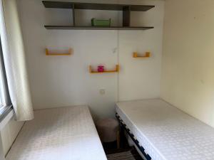 two beds in a small room with shelves at Mobil-home proche plage in Saint-Julien-en-Born +14 photos