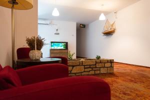 a living room with two red chairs and a tv at Hotel Mercur in Eforie Sud