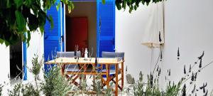 a table and chairs in front of a house with a blue shutter at Fragos Apartments in Santa Maria