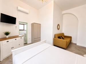 a white bedroom with a large bed and a chair at Hotel Cazino Nord in Mamaia