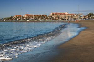 a beach with people walking on the sand and water at Apartamentos Vista Sur in Playa de las Americas