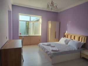 a bedroom with a bed with purple walls and a window at Bright Modern Suite in Quba