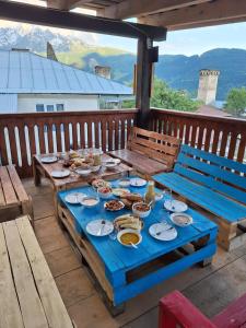 a blue table with plates of food on a deck at Guest House Gvidani In Lakhiri in Mestia