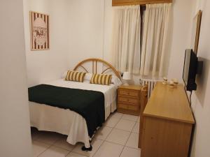 a bedroom with a bed and a dresser and a television at Hostal La Madrileña in La Gudiña