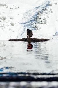 a woman sitting on a surfboard in the water at Hotel Zürserhof in Zürs am Arlberg +159 photos