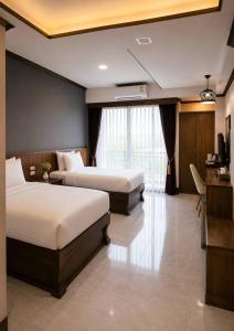 a hotel room with two beds and a desk at Chomphu Phukha Resort-Mountain View Nan in Pua