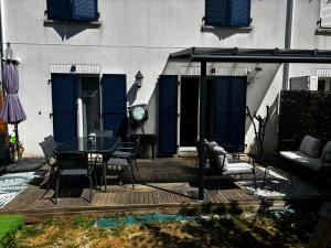 a patio with a table and chairs and blue shutters at Disney - Résidence Juan Valera in Vaujours