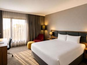 a hotel room with a large bed and a red chair at Novotel Sydney International Airport in Sydney
