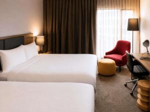 a hotel room with a bed and a red chair at Novotel Sydney International Airport in Sydney +99 photos