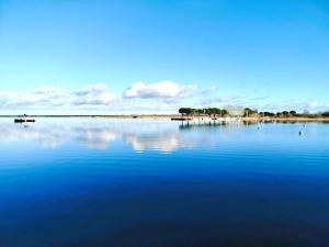 a large blue lake with a boat in the water at Logement à deux pas du lac Carcans Maubuisson in Carcans