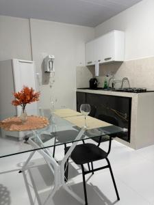a kitchen with a glass table and chairs in a kitchen at Kitnet Vista do Vale in Areia