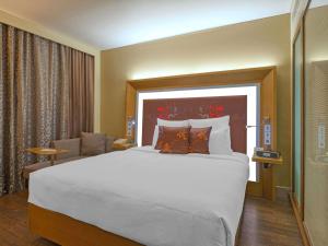 a hotel room with a large bed and a chair at Novotel Bengaluru Outer Ring Road in Bangalore