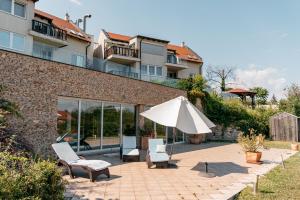 a patio with two chairs and an umbrella at Tihany Panoráma Apartman in Tihany