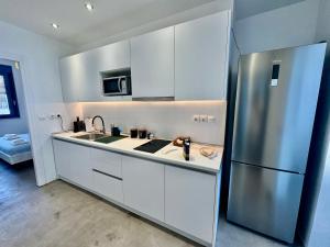 a kitchen with white cabinets and a stainless steel refrigerator at NV seafront Villa with private pool & NV seafront luxury suites no pool acces - Aegina in Áyioi