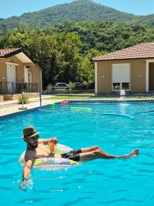 a man in a swimming pool with a drink in a swimming pool at Etno Selo Grabovicka Jutra in Cetinje +57 photos