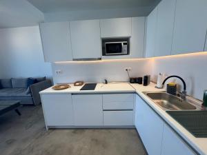 a white kitchen with a sink and a microwave at NV seafront Villa with private pool & NV seafront luxury suites no pool acces - Aegina in Áyioi