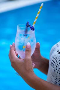 a person holding a glass with a straw in it at Etno Selo Grabovicka Jutra in Cetinje