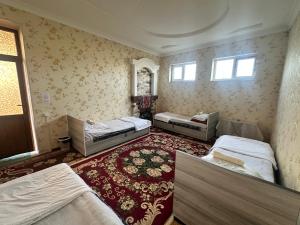 a bedroom with three beds and a red carpet at JOMIY Guest House in Margilan