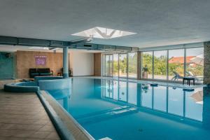 a large swimming pool with blue water in a building at Tihany Panoráma Apartman in Tihany