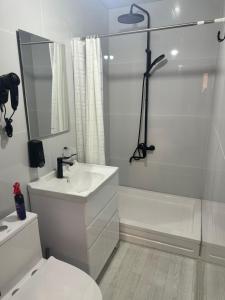 a white bathroom with a sink and a shower at JOMIY Guest House in Margilan