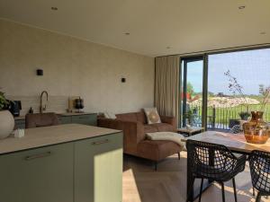 a kitchen and living room with a couch and a table at B&B Het Houten Huis in Brandwijk