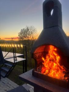 a fire oven with a bench and a sunset in the background at Nature View Breaza in Breaza de Sus