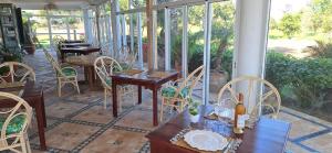 a conservatory with tables and chairs and a room with windows at Le Refuge in Larache