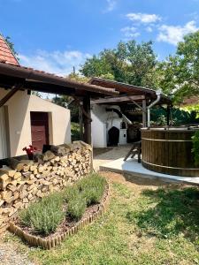 a patio with a stone wall and a wooden pergola at Zselic Kuckó by Mártika in Szigetvár