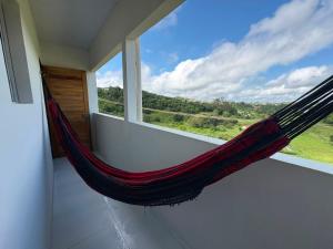 a hammock in a room with a large window at Kitnet Vista do Vale in Areia