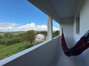 a hammock in a room with a view of a house at Kitnet Vista do Vale in Areia +7 photos