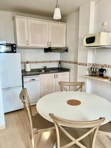 a white kitchen with a white table and chairs at Puebla :) in A Pobra do Caramiñal