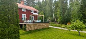 a red house with a deck on a lawn at Lottefors Logi in Bollnäs
