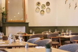 a dining room with tables and chairs and a mirror at Le Presbytère in Ambleteuse