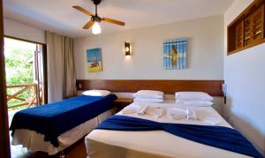 a bedroom with two beds and a ceiling fan at Pousada Windjeri in Jericoacoara