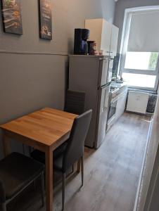 a small kitchen with a wooden table and a refrigerator at FördeNest in Flensburg
