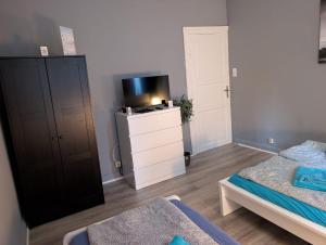 a bedroom with a bed and a tv and a dresser at FördeNest in Flensburg