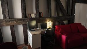 a room with a desk with a computer and a red couch at Appart proche gare centre ville bureau parking in La Loupe +14 photos