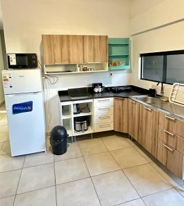 a kitchen with a white refrigerator and wooden cabinets at CDE House in Ciudad del Este