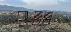two wooden chairs sitting on top of a hill at Lebentera camp in Narok