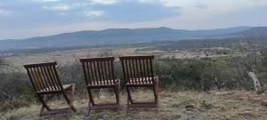 two wooden chairs sitting on top of a hill at Lebentera camp in Narok