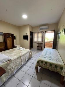 a hotel room with two beds and a television at Bela Vista in Canoa Quebrada
