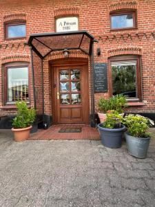 a brick building with a wooden door and potted plants at Helles 3 Bett Zimmer in Jerrishoe