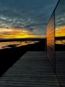a wooden boardwalk with a sunset in the background at Mystic Light Lodge in Búðardalur