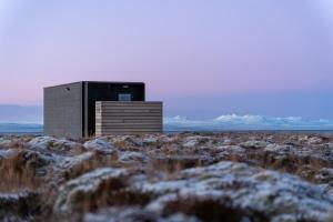 a small building in the middle of a snowy field at Mystic Light Lodge in Búðardalur