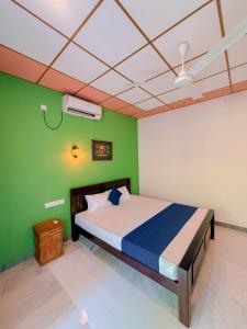 a bedroom with a bed and a green wall at Deer Inn - Yala in Tissamaharama