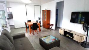a living room with a couch and a tv and a table at Villa Palétuvier Ste Luce Martinique proche plage in Sainte-Luce