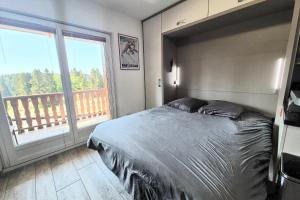 a bedroom with a bed and a large window at Cozy apartment "WAPITI" at the foot of the slopes in Les Déserts