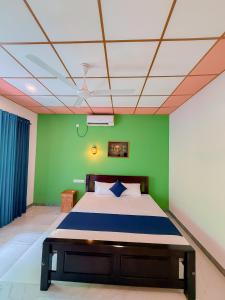 a bedroom with a bed and a green wall at Deer Inn - Yala in Tissamaharama